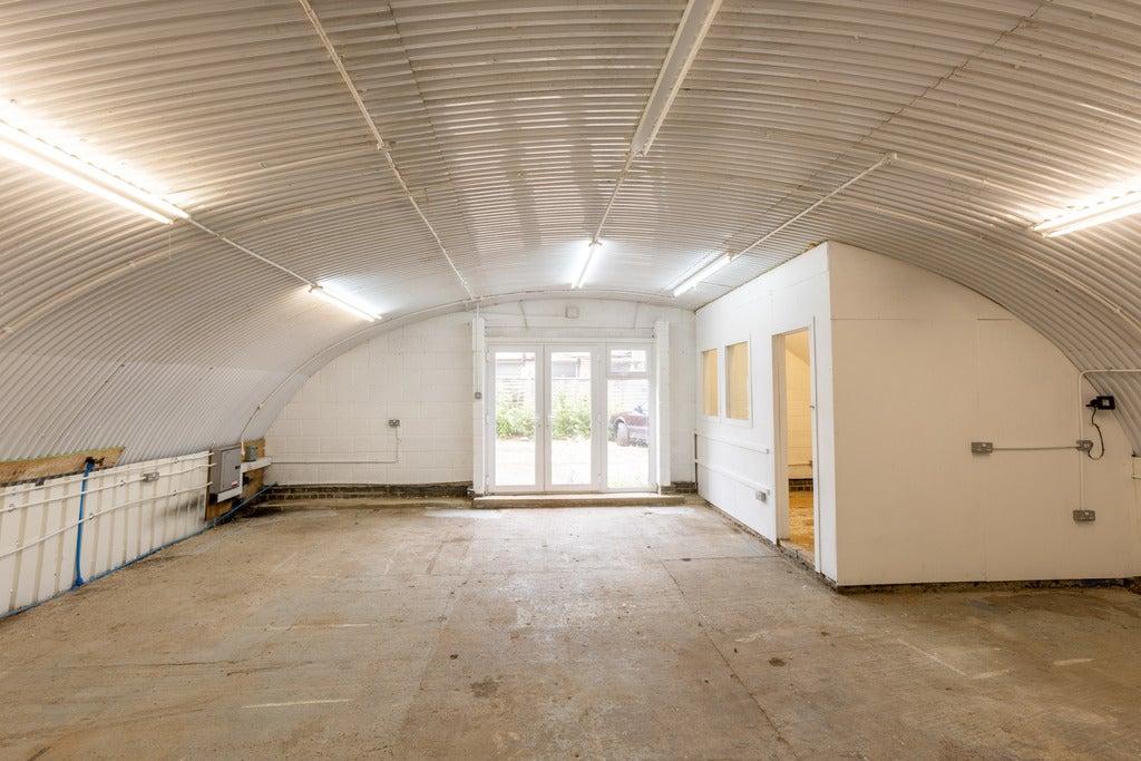 An empty arch with white lining, and an office unit at the back.