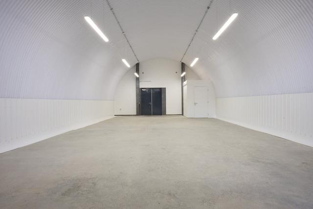 An empty arch with white lining and a fire escape door at the back.