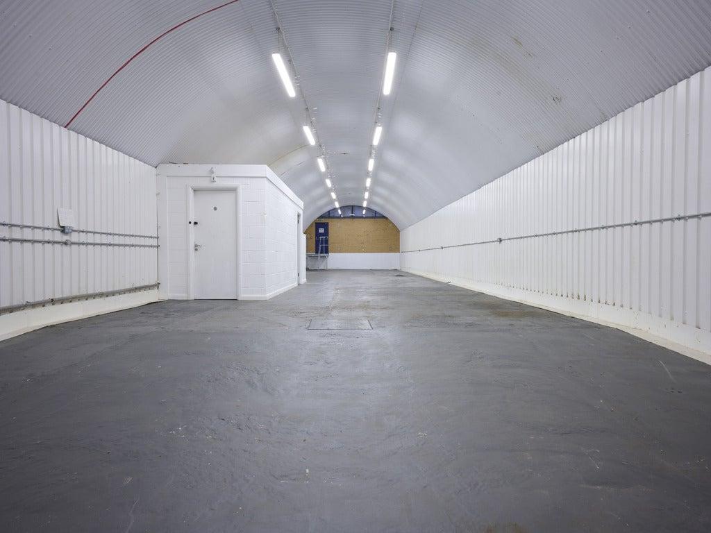 An empty arch with white lining and a WC cubicle to the back.