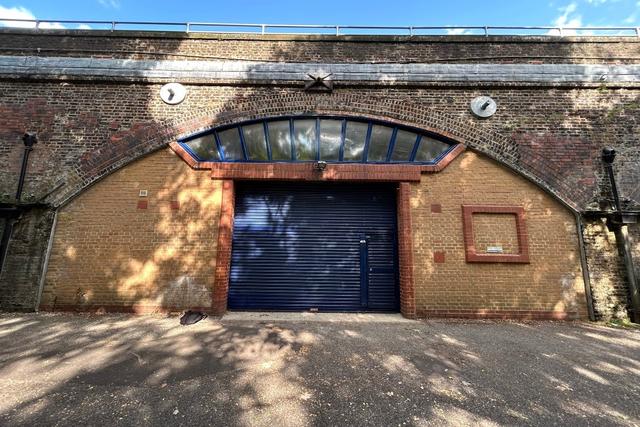 The front of an arch with a closed electric roller shutter entrance big enough for vehicle access. 