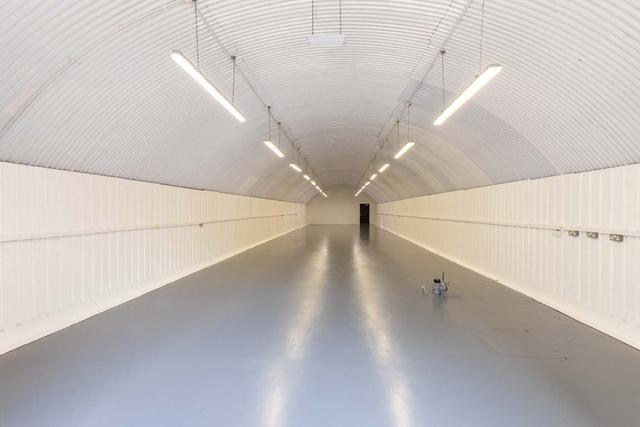 An empty arch with white lining, facing the front electric roller shutter entrance, which is open.