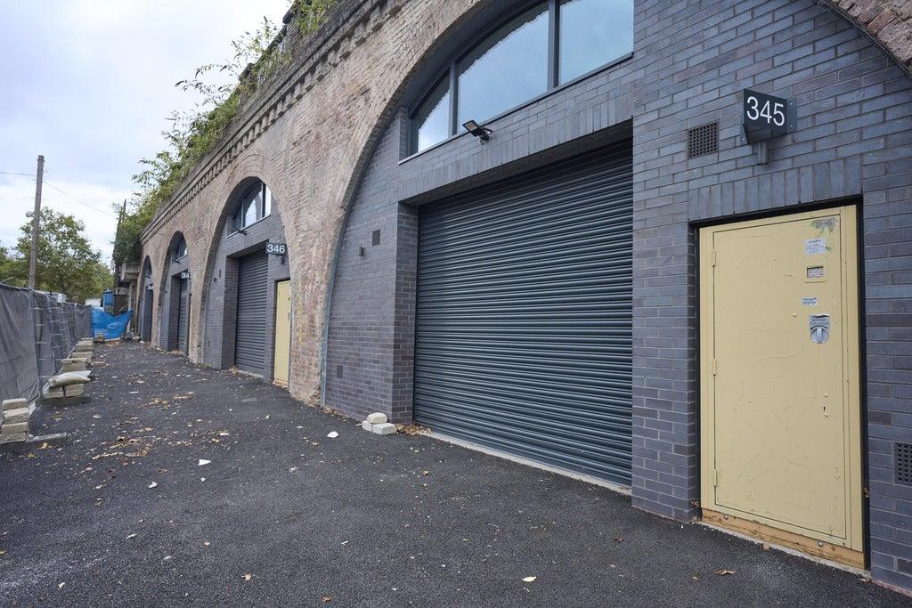 The front of an arch, with high level glazing, a closed electric roller shutter entrance big enough for vehicle access, and a pedestrian door.