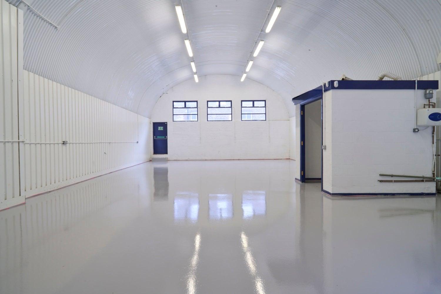 An empty arch with white lining and a WC cubicle to the back.